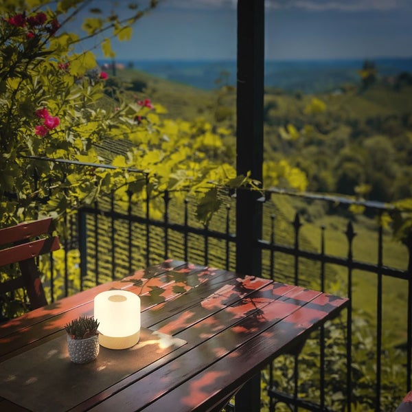 Akkubetriebene LED-Leuchte auf einem gedeckten Gartentisch mit Salatschüssel und Gläsern im Garten.