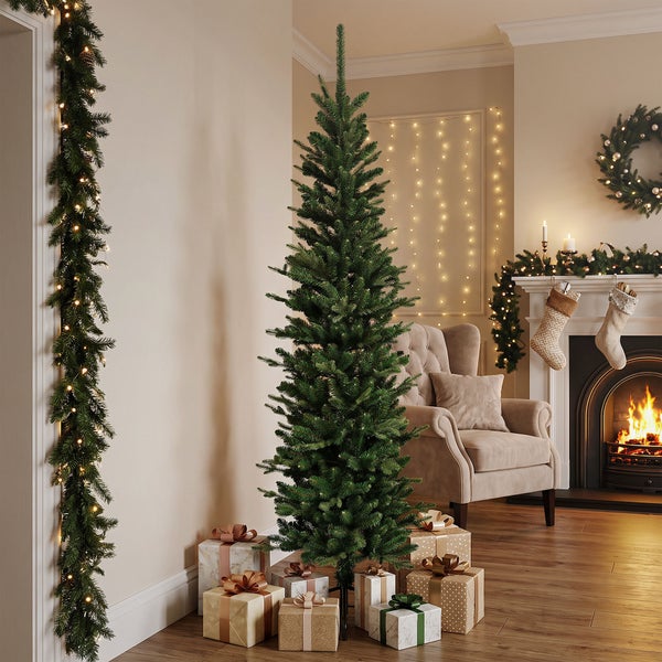 Ein künstlicher Weihnachtsbaum steht neben Geschenken in einem weihnachtlich dekorierten Wohnzimmer mit Kamin und Girlanden.