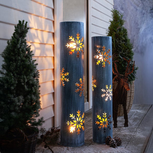 Zwei dekorative Windlichter mit Schneeflockenmuster im Außenbereich.