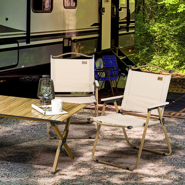 Campingplatzszene mit Holztisch, Campingstühlen, Lampe und Wohnwagen