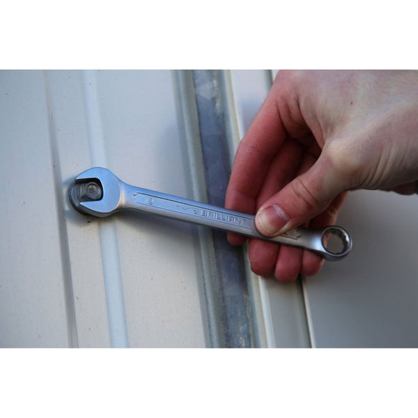 Ein Maulschlüssel der Größe 12 wird von einer Hand gehalten und an einer Schraube befestigt.