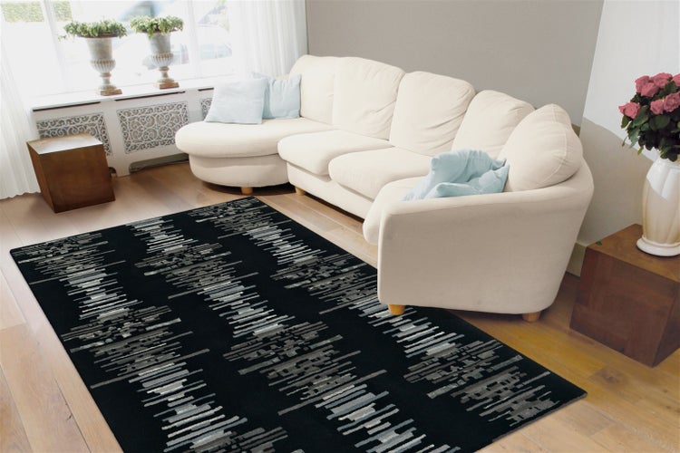 Wohnzimmer mit hellem Sofa und einem rechteckigen Teppich mit abstraktem Muster auf Holzboden in einem modern eingerichteten Raum.
