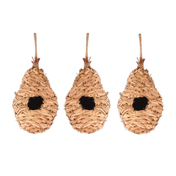 Zwei hängende Vogelnester aus Naturmaterial mit einem Zebrafinken auf einem Ast.
