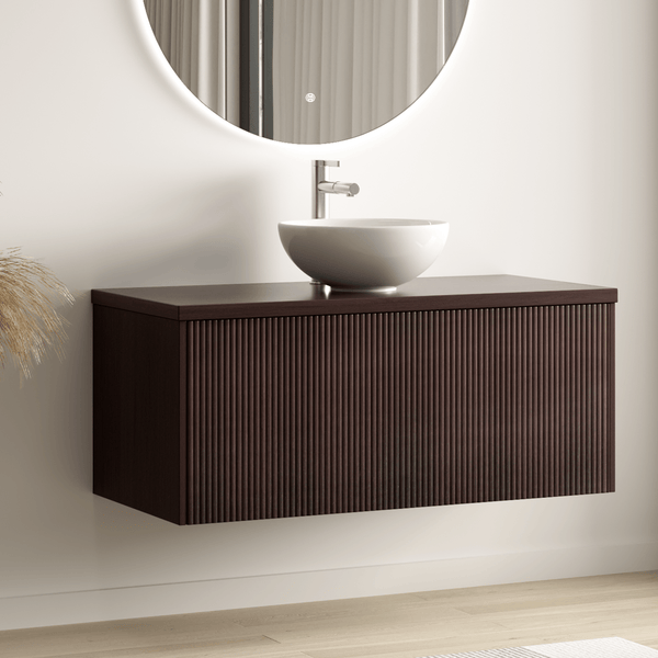 Modernes Badezimmer mit wandhängendem Waschtischunterschrank aus Holz mit geriffelter Front, rundem Aufsatzbecken und beleuchtetem Rundspiegel.