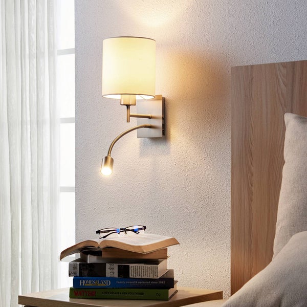 Moderne Wandleuchte mit hellem Stoffschirm und flexiblem Lesearm aus Metall, montiert neben einem Bett im Schlafzimmer.