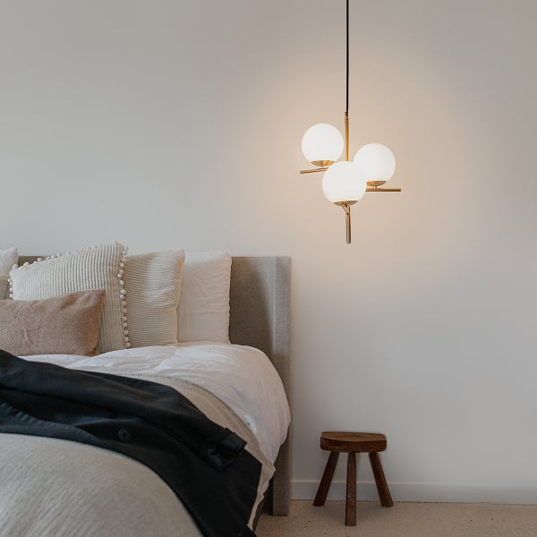 Schlafzimmer mit Bett und Hängelampe mit drei Lampenschirmen