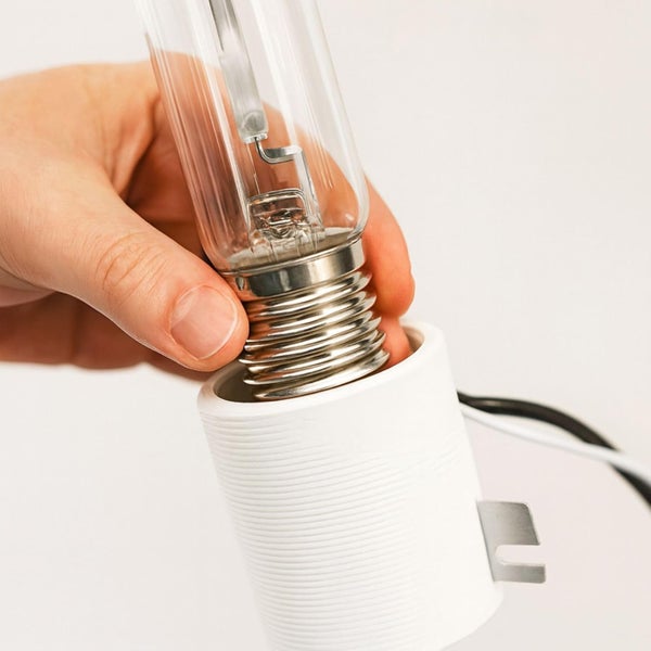 Hand setzt ein klares, röhrenförmiges Leuchtmittel mit Schraubsockel in eine weiße Fassung ein.