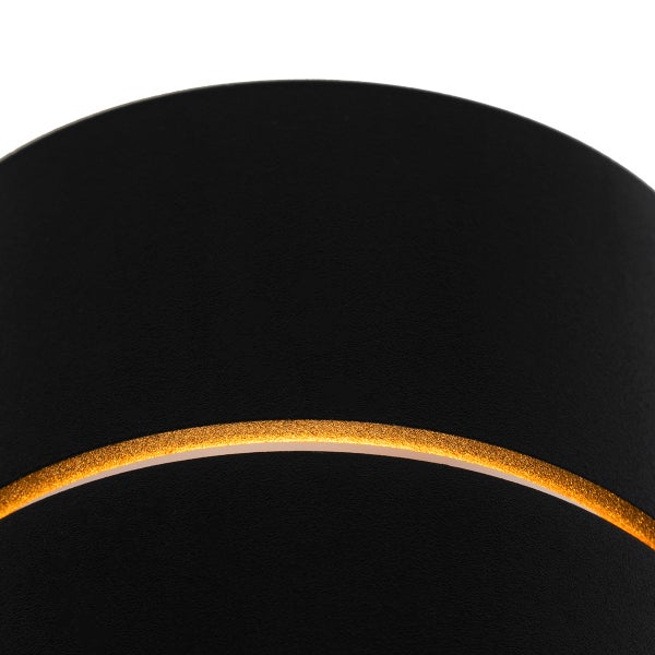 Detailaufnahme einer runden, schwarzen Leuchte mit goldenem Zierstreifen.