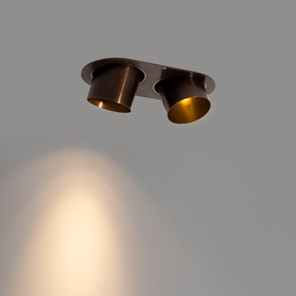 Zweiflammiger Deckenstrahler in Dunkelbraun mit eingeschaltetem warmem Licht.