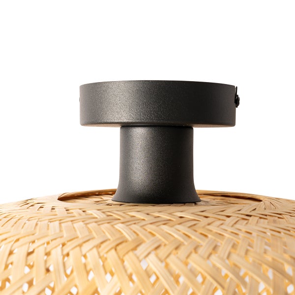 Detailaufnahme einer Deckenlampe mit Lampenschirm aus Rattan und schwarzer Metallaufhängung.