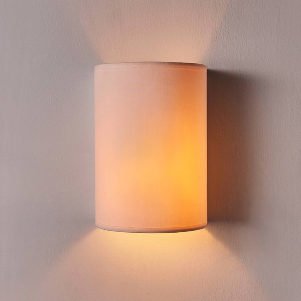 Zylindrische Wandleuchte mit Stoffschirm und Lichtauslass nach oben und unten an einer strukturierten Wand.