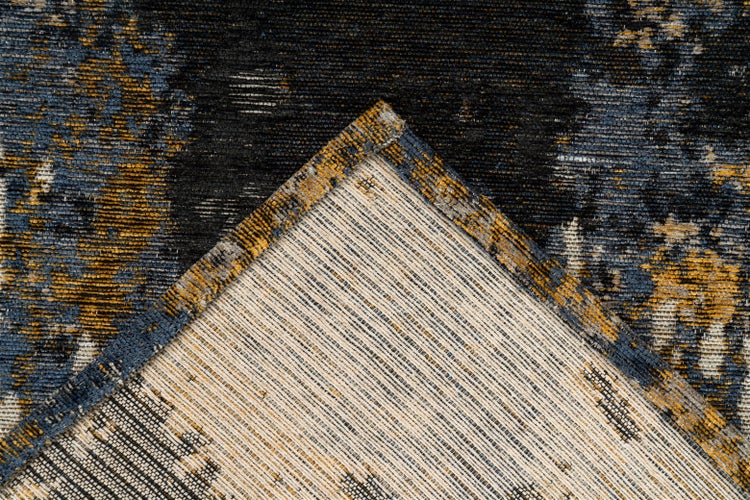 Nahaufnahme eines Teppichs mit abstraktem Muster und umgeknickter Ecke zur Ansicht der Rückseite.