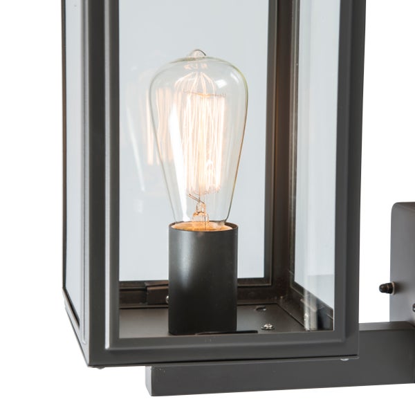 Schwarze Außenwandleuchte in Laternenform aus Metall und Glas mit leuchtendem Vintage-Leuchtmittel.