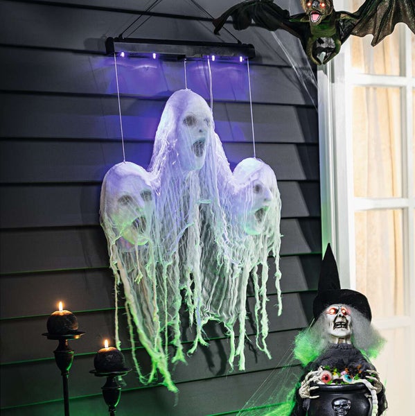 Szene mit Halloween-Dekorationen, darunter Geister, Fledermaus, Kerzen und Hexenfigur für eine gruselige Atmosphäre.