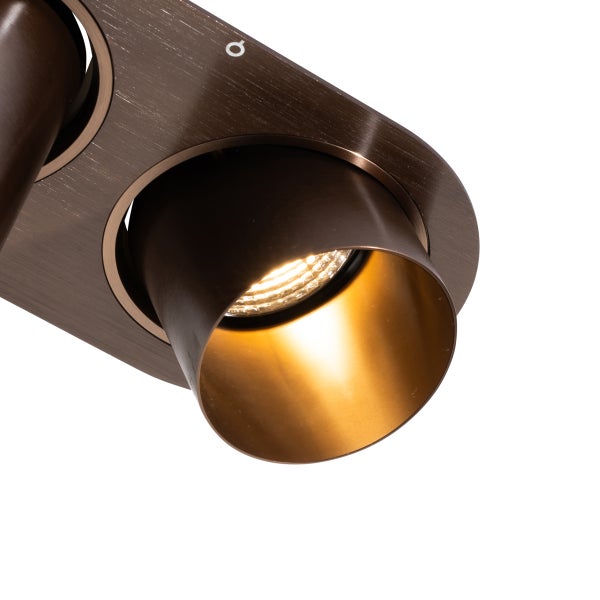 Deckenstrahler aus gebürstetem Metall mit verstellbarem Spot und warmem Licht.