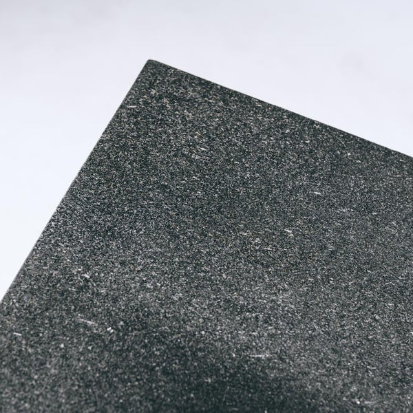 Detailaufnahme einer feinkörnigen, dunklen Granitplatte mit strukturierter Oberfläche.