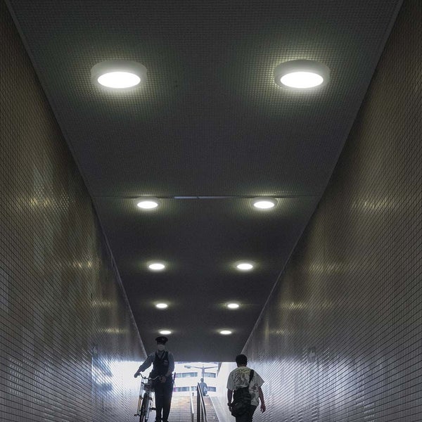 Unterführung mit runden Deckenleuchten und Passanten