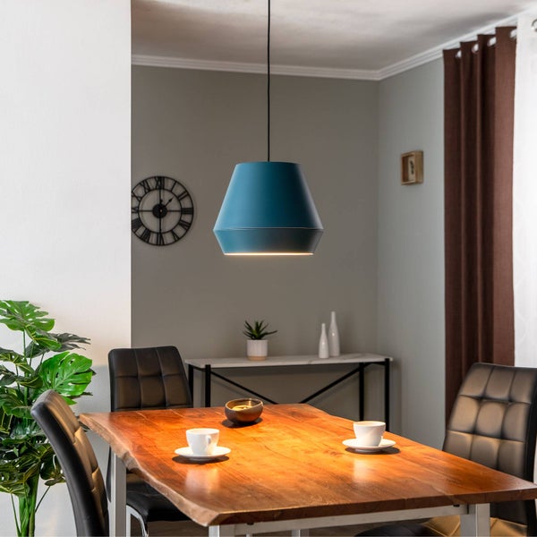 Moderne Pendelleuchte in Blau über einem massiven Holztisch in einem hellen Esszimmer mit schwarzen Stühlen und Wanduhr.