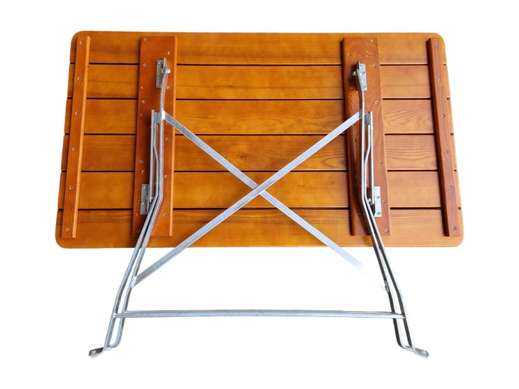 Klappbarer Gartentisch aus Holzlatten mit Metallgestell, Ansicht von unten mit Klappmechanismus.