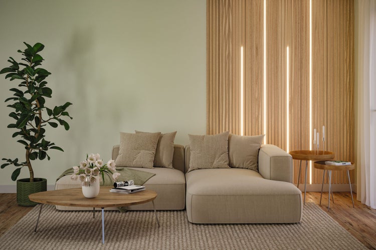 Modernes Wohnzimmer mit hellem Ecksofa, Holzwand mit LED-Streifen, Couchtisch aus Holz, Zimmerpflanze und Teppich in hellem, strukturiertem Design.