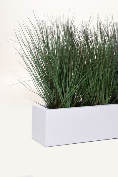 Künstliches Gras in einem rechteckigen weißen Pflanzkasten.