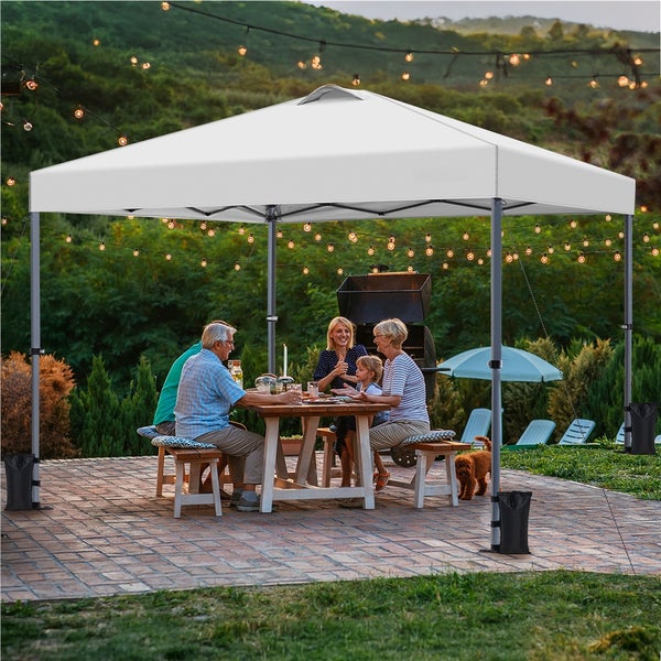 Szene im Freien mit einem weißen Pavillon, unter dem eine Familie an einem Tisch sitzt