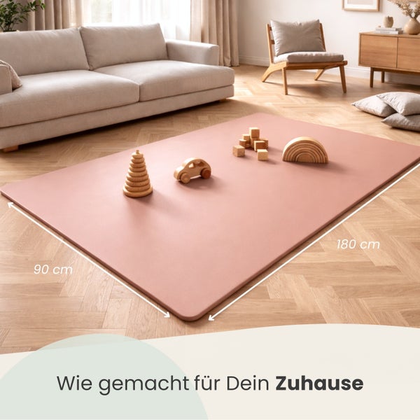 Rechteckige rosa Spielmatte aus Schaumstoff mit Holzspielzeug in einem hellen Wohnzimmer. Maße: 90 mal 180 Zentimeter.