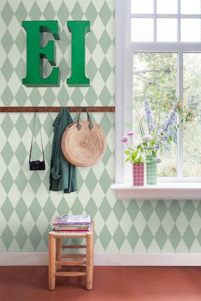 Flur mit Rautenmuster-Tapete, Garderobe, Dekoration und Fenster für einen hellen Eindruck.