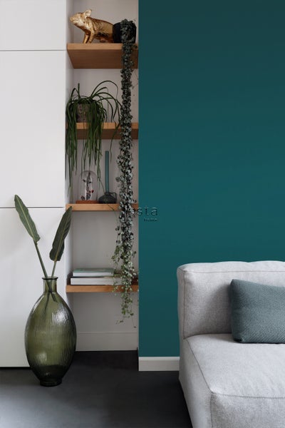 Wohnzimmer mit Regalen, Grünpflanzen und grauem Sofa.