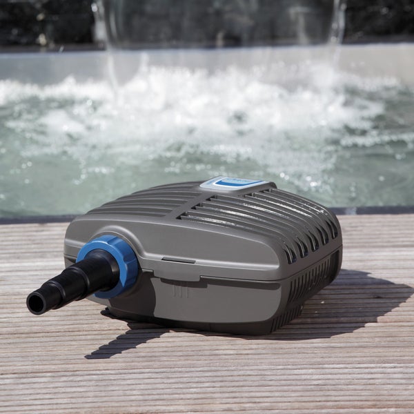 Graue Teichpumpe aus Kunststoff mit Stufenschlauchtülle auf einem Holzdeck vor einem Wasserspiel.