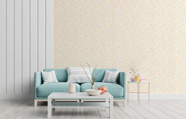 Wohnzimmer mit Vliestapete mit Blumenmuster an der Wand und einem Sofa in einer hellen Einrichtung.