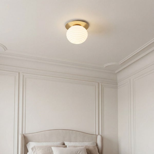 Runde Deckenleuchte mit geriffeltem Glasschirm und Messinghalterung in einem hellen Raum mit klassischen Wandleisten.