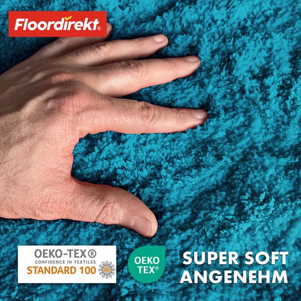 Hand berührt weichen, blauen Teppich mit Floor Direkt Logo sowie OEKO-TEX Siegel.