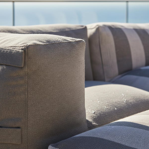 Nahaufnahme von wasserabweisenden Garten-Loungekissen aus strukturiertem Stoff mit Wassertropfen auf der Oberfläche.