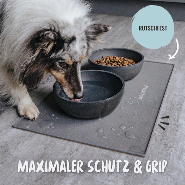 Hund trinkt Wasser aus einem Napf auf einer rutschfesten Unterlage mit der Aufschrift Rudelkoenig.