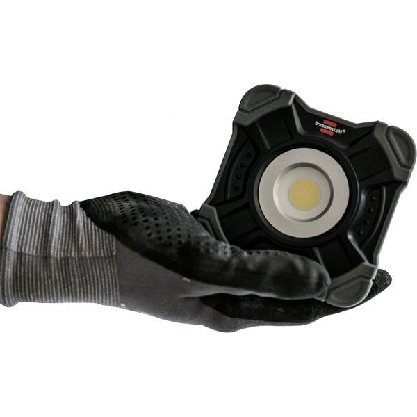 Eine Hand in einem Arbeitshandschuh hält eine Brennenstuhl Arbeitsleuchte.