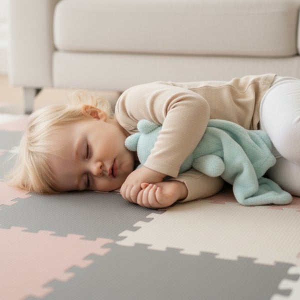 Schlafendes Kleinkind auf einer Puzzlematte aus Schaumstoff im Kinderzimmer.