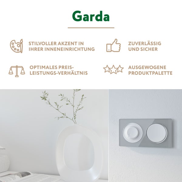 Garda Schalterprogramm mit Lichtschalter und Dimmer an einer hellen Wand neben einer Vase und einem Buch.