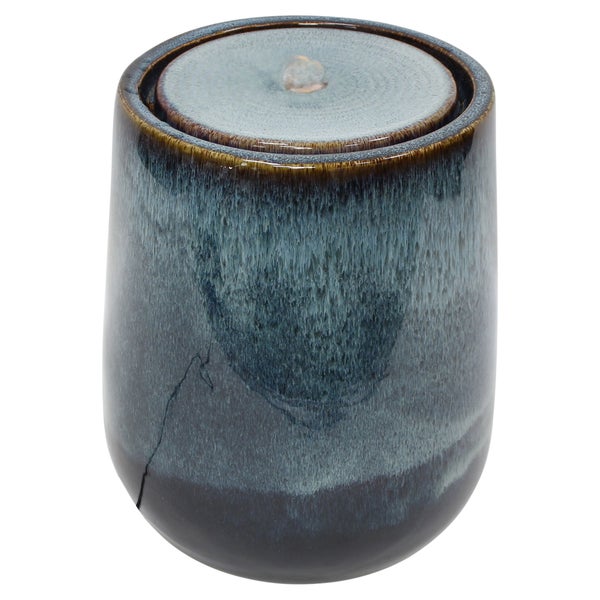 Zylindrischer Gartenbrunnen aus glasierter Keramik mit sprudelndem Wasser auf der Oberseite.