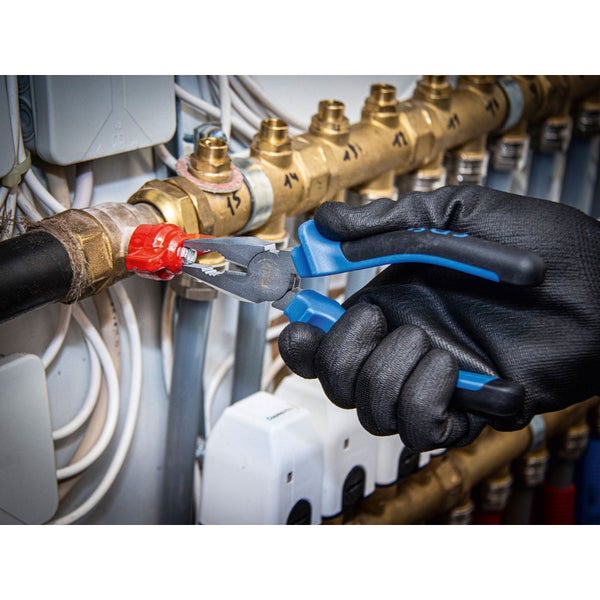 Eine Person mit Arbeitshandschuhen verwendet eine Zange an einem Heizungsrohr.