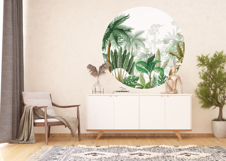 Wohnzimmer mit einem Wandaufkleber mit Dschungelmotiv über einem weißen Sideboard.