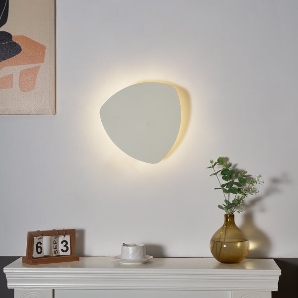 Weiße, dreieckige Wandleuchte zur indirekten Beleuchtung an einer Wand