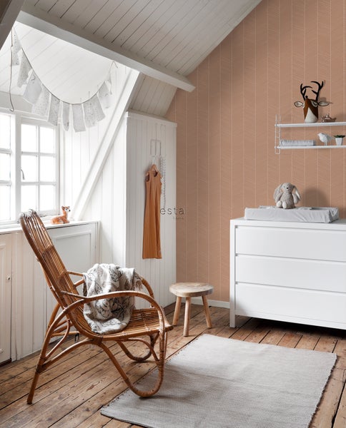 Helles Kinderzimmer mit Wickelkommode, Holzstuhl, Rattan Sessel und gemusterter Tapete