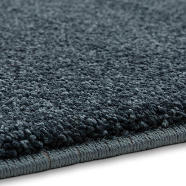 Nahaufnahme eines dunkelgrauen Hochflor-Teppichs mit gekettelter Kante.