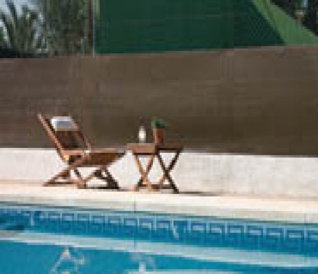 Braune Sichtschutzmatte am Pool mit Liegestuhl und Beistelltisch aus Holz.