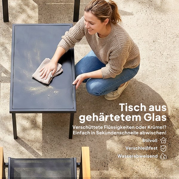 Frau reinigt einen modernen Gartentisch aus gehärtetem Glas und Metall mit einem Tuch. Die Oberfläche ist verschleißfest und wasserabweisend.