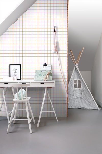 Hell gestalteter Kinderarbeitsplatz mit weißem Schreibtisch, Stuhl und bunter Karotapete. Ein gestreiftes Spielzelt steht im Hintergrund.