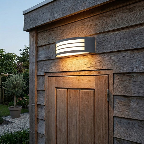 Moderne Außenwandleuchte mit horizontalen Lichtschlitzen, montiert an einem Gartenhaus aus Holz über der Tür.