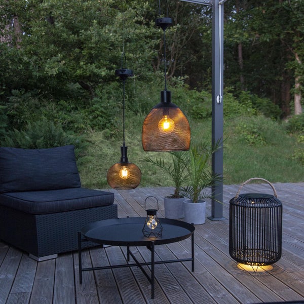 Gartenlounge mit schwarzem Loungesessel, Couchtisch und mehreren Solarleuchten auf einer Terrasse