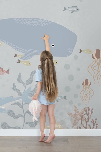Mädchen berührt Wandbild mit Meeresmotiven im Kinderzimmer